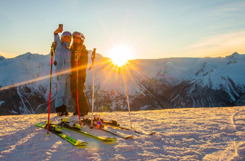 Zwei Skifahrerinnen machen ein Selfie bei Sonnenaufgang auf verschneitem Gipfel | © Gasteinertal Tourismus GmbH