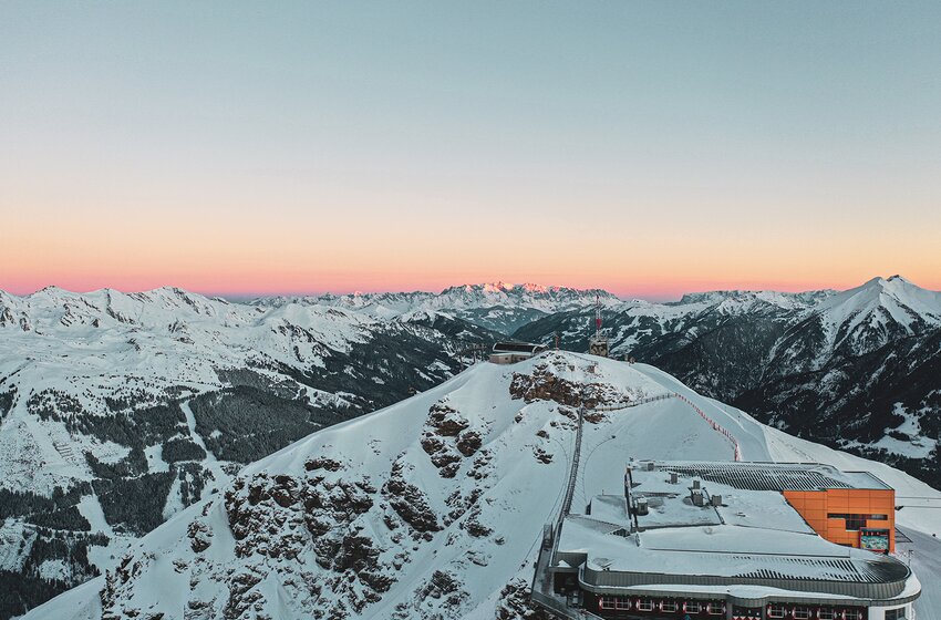 Panoramaaufnahme mit verschneiten Bergen, Gipfelstation und rosa Sonnenaufgang | © Gasteinertal Tourismus GmbH