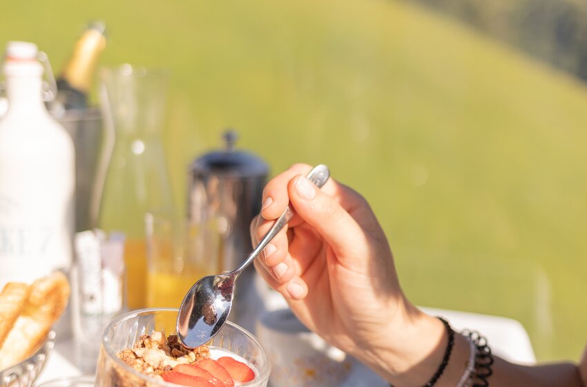 Person löffelt Joghurt mit Erdbeeren und Müsli an Tisch in einer Berggondel bei sonnigem Wetter | © Großarler Bergbahnen GmbH & Co KG