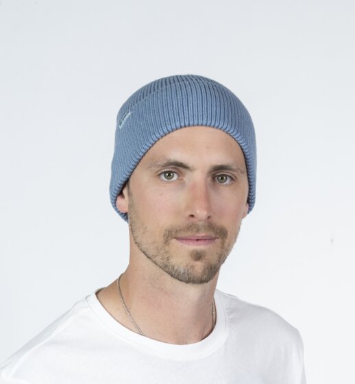 Mann trägt hellblaue Ski amadé Mütze und weißes Shirt vor hellem Studiohintergrund | © Ski amadé GmbH