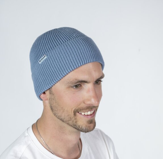 Man wearing light blue Ski amadé beanie and white shirt in front of bright backdrop | © Ski amadé GmbH / Lorenz Masser