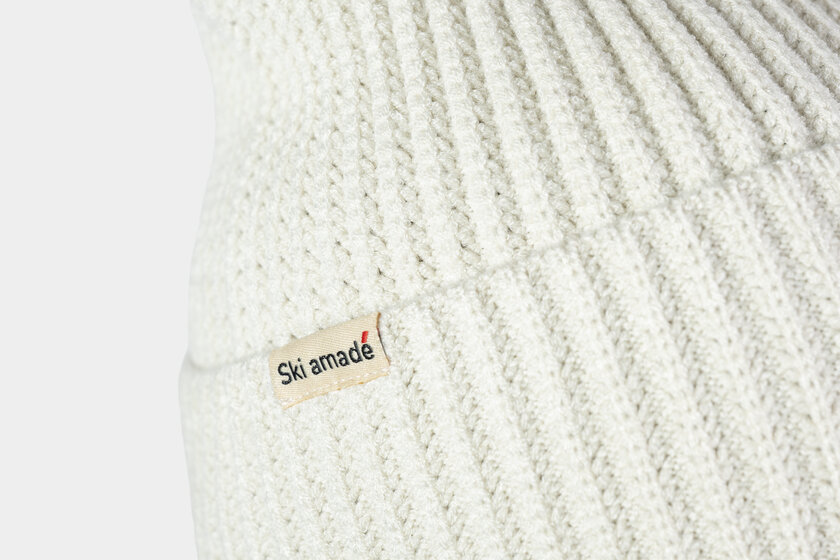 Cremeweiße, strukturierte Strickmütze mit Ski amadé Logo auf einem Stoffetikett | © Ski amadé GmbH