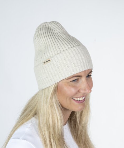 Woman in cream white Ski amadé beanie and white shirt against bright backdrop | © Ski amadé GmbH / Lorenz Masser