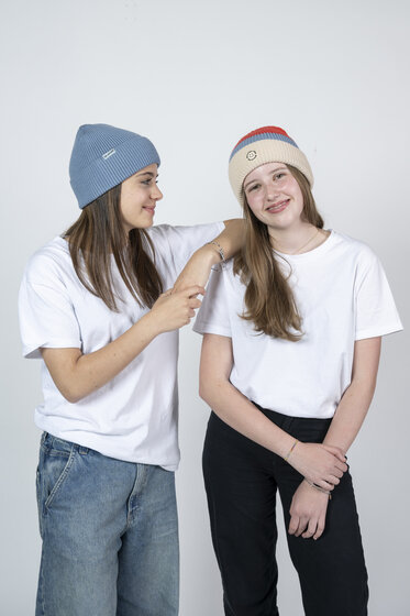 Two girls in white shirts with Ski amadé beanies standing and smiling together | © Ski amadé GmbH / Lorenz Masser