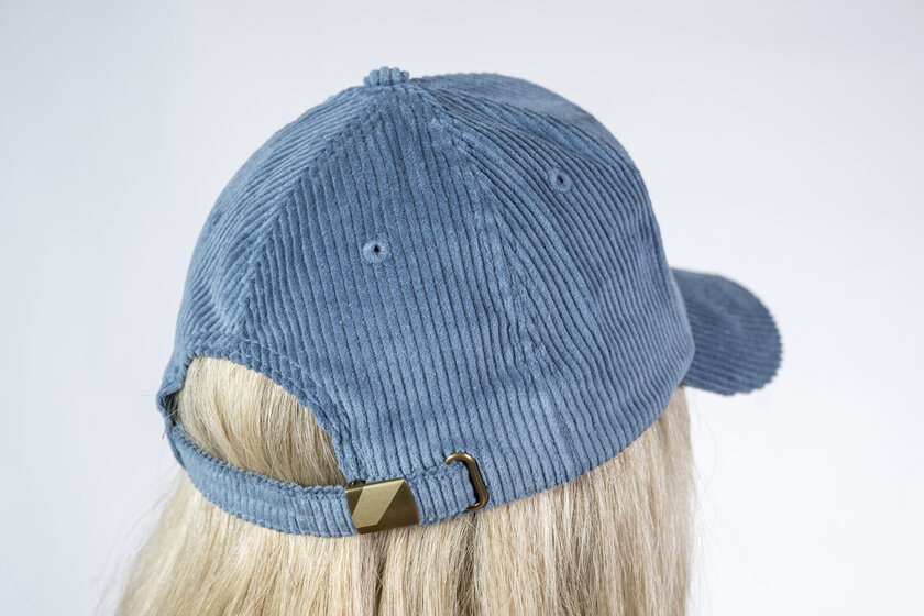 Rear view of a blue cord baseball cap with adjustable metal strap on the head of a blonde person | © Ski amadé GmbH / Lorenz Masser