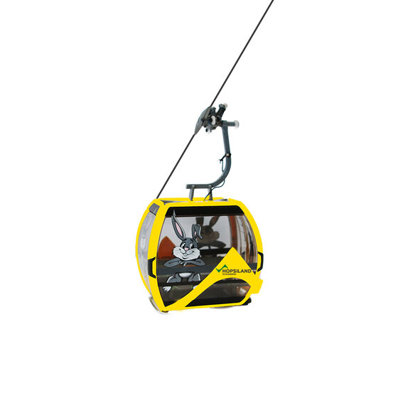 Gelbe Seilbahngondel mit Hasenmotiv und Hopsiland-Schriftzug auf der Frontseite in der Luft | © Planai-Hochwurzen-Bahnen GmbH