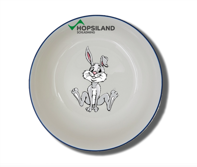 Weiße Kinderschale mit blauem Rand, im Inneren sitzender Hopsi-Hase und Hopsiland-Schriftzug am oberen Rand | © Planai-Hochwurzen-Bahnen GmbH