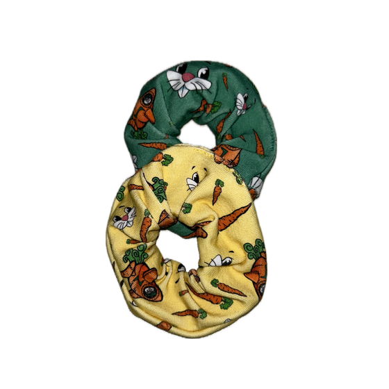 Zwei bunte Kinder-Haargummis mit Hasengesichtern, Karotten und Hasenmotiven auf grünem und gelbem Stoff | © Planai-Hochwurzen-Bahnen GmbH