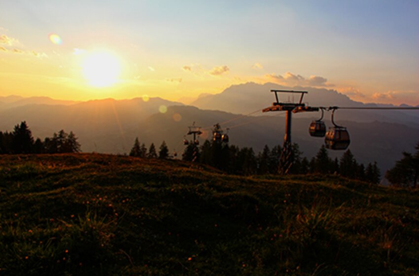 Cable car at Geisterberg in the soft glow of sunrise | © Snow Space Salzburg Bergbahnen Cable car at Geisterberg glides over autumn meadows at sunrise with scenic mountain silhouettes and a golden glowing sky. | © Snow Space Salzburg Bergbahnen