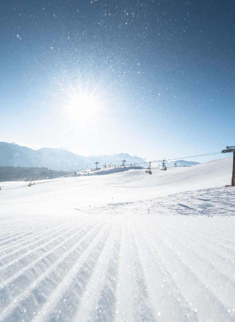 Sessellifte über einer weiten Schneelandschaft, im Vordergrund eine Piste bei Sonnenaufgang mit glitzernden Kristallen. | © Ski amadé GmbH