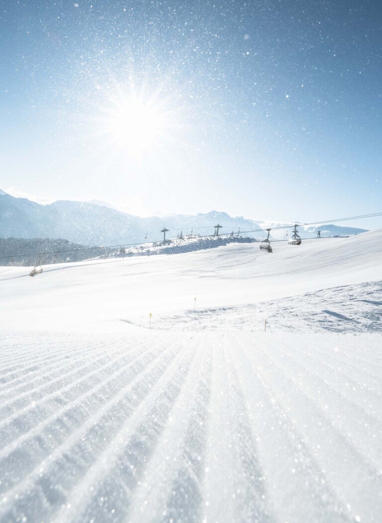 Sessellifte über einer weiten Schneelandschaft, im Vordergrund eine Piste bei Sonnenaufgang mit glitzernden Kristallen. | © Ski amadé GmbH
