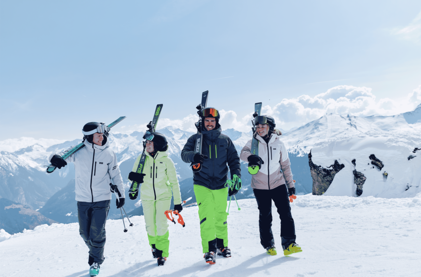 Vier Skifahrer gehen mit Ski und Stöcken über eine verschneite Piste, dahinter erheben sich schneebedeckte Berge. | © Gasteiner Bergbahnen AG 