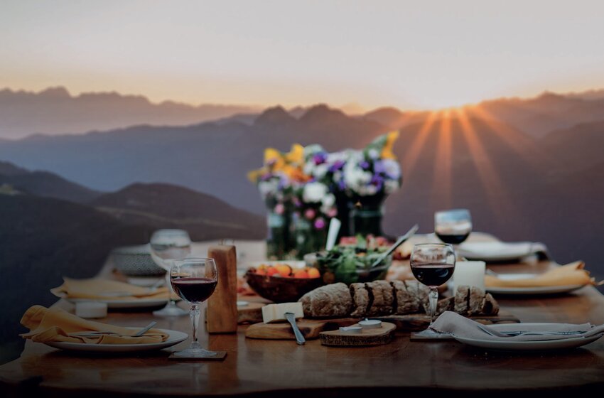 Festive table with bread, wine and flowers at sunset in the mountains – atmospheric and scenic setting | © Zauchensee Liftgesellschaft Benedikt Scheffer GmbH