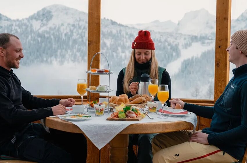 Three people having breakfast with pastry, juice and coffee in front of snowy mountains. | © Zauchensee Liftgesellschaft Benedikt Scheffer GmbH
